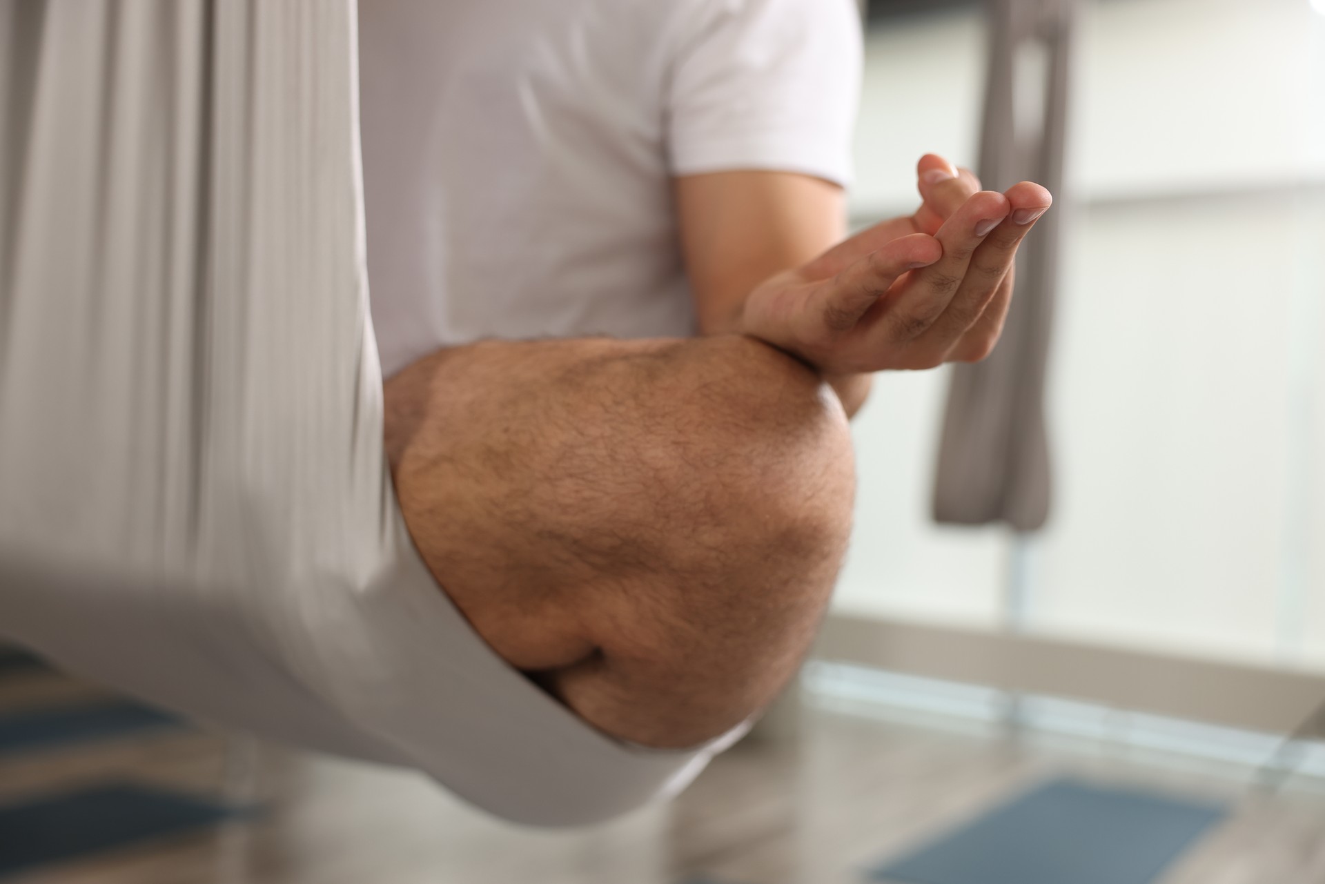 Man meditating in fly yoga hammock indoors, closeup